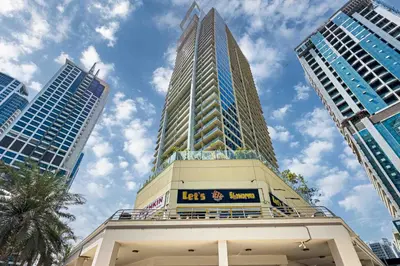 a tall building with a sign on the top of it at Chill Studio with Balcony and Pool View in Dubai