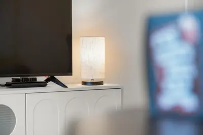 a lamp sitting on a table next to a television at FIRST CLASS 1BR Spacious Comfort Awaits in Dubai