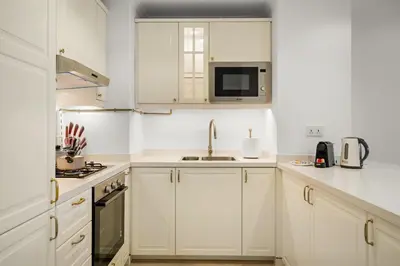 a white kitchen with white cabinets and a sink at FIRST CLASS 1BR Spacious Comfort Awaits in Dubai