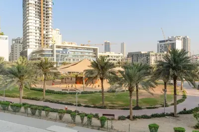 a park with palm trees in front of a city at FIRST CLASS 1BR Spacious Comfort Awaits in Dubai