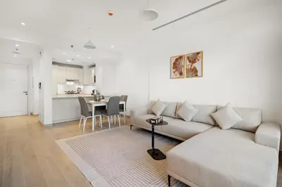 a white living room with a couch and a table at FIRST CLASS 1BR Spacious Comfort Awaits in Dubai