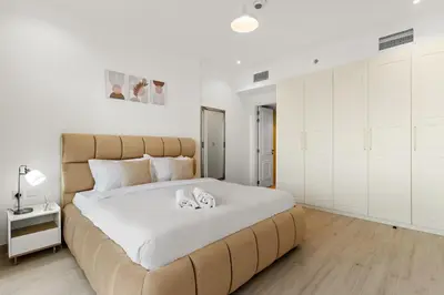 a bedroom with a large bed with white walls at FIRST CLASS 1BR Spacious Comfort Awaits in Dubai