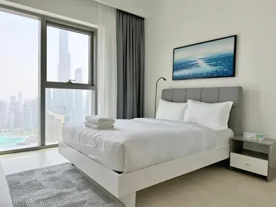 a white bedroom with a bed and a large window at DVR 4 BR Apartment available in Downtown View 2 in Dubai