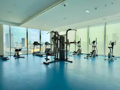 a gym with cardio equipment in a large room with windows at Brand New - Fully Furnished Premium 1BR in JVC in Dubai