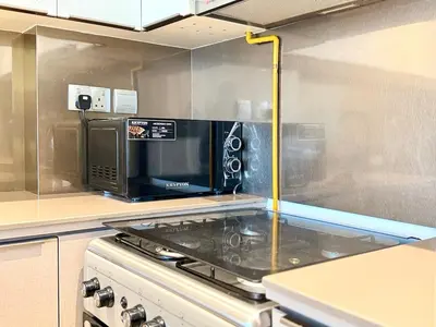 a kitchen with a microwave and a stove top at Brand New - Fully Furnished Premium 1BR in JVC in Dubai