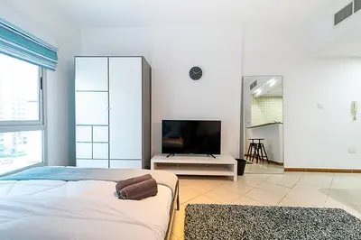 a bedroom with a bed and a flat screen tv at Cozy Chic Studio l Next to Marina Mall in Dubai