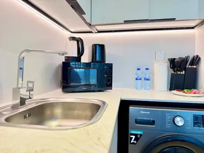a kitchen with a sink and a washing machine at Brand New-Fully Furnished Classy Studio In JVC in Dubai