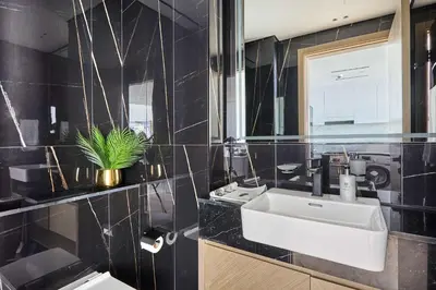 a black tiled bathroom with a sink and a mirror at Frank Porter - Binghatti Corner in Dubai