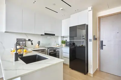 a kitchen with white cabinets and a black refrigerator at Frank Porter - Binghatti Corner in Dubai