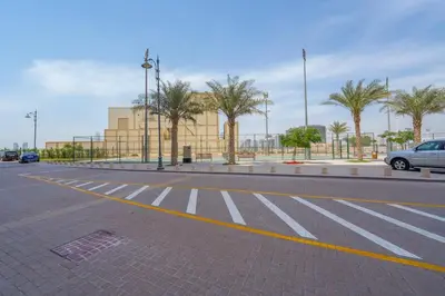 an empty street with a parking lot with palm trees at 1BHK Luxury Serviced Apartment - Al Andalus JGE in Dubai
