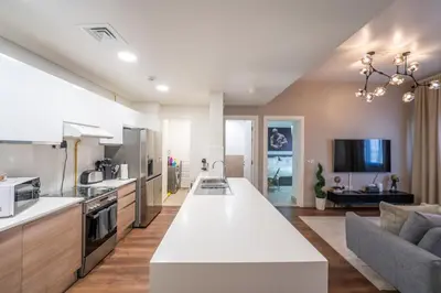 a kitchen and living room with a large white counter top at 1BHK Luxury Serviced Apartment - Al Andalus JGE in Dubai