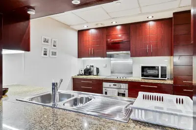 a kitchen with a stainless steel sink and wooden cabinets at Vibrant 1BR APT with Burj Khalifa View in Dubai