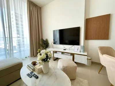 a living room with a tv and a couch and a table at Elegant Jvc 1br Balcony, Pool Access, Parking in Dubai