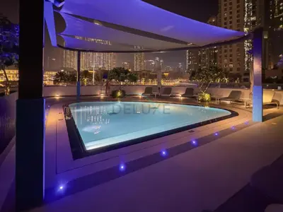 a swimming pool on top of a building at night at City Vibe 1BR with Outdoor Space, Walking Distance to Burj Khalifa and Dubai Mall, Grande, Downtown Dubai by Deluxe Holiday Homes in Dubai