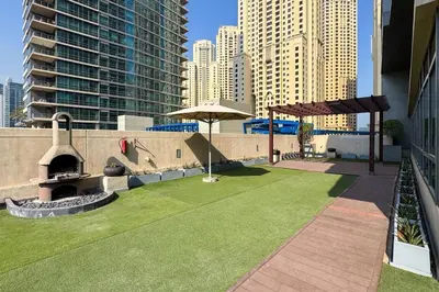 a rooftop patio with a lawn and an umbrella at GuestReady - Contemporary living in Dubai Marina in Dubai