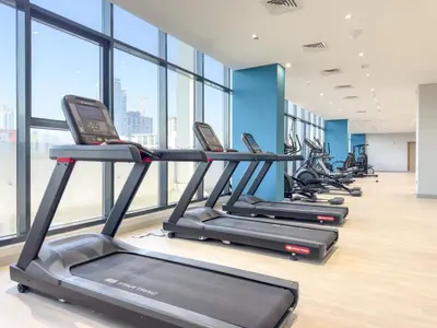 a row of treadmills in a gym with windows at FIRST CLASS Studio Urban Elegance in Dubai