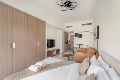 a bedroom with a large bed and a living room at FIRST CLASS Studio Urban Elegance in Dubai