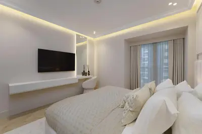 a white bedroom with a large bed and a flat screen tv at Daniels 4BR At Princess Tower with Marina and Sea view in Dubai