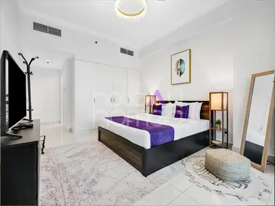 a bedroom with a large bed and a tv at Modern 1BR Oasis II Huge Layout II City Lights in Dubai