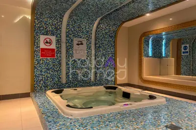 a bathroom with a jacuzzi tub and a mirror at Modern 1BR Oasis II Huge Layout II City Lights in Dubai