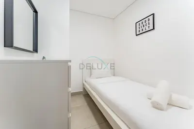 a white bedroom with a bed and a mirror at Balcony Offering Community Views 1BR with Assistant Room, Walking Distance to Community Park , Pantheon Elysee , Jumeirah Village Circle by Deluxe Holiday Homes in Dubai