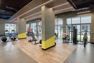 a gym with tread machines and people in the background at Balcony Offering Community Views 1BR with Assistant Room, Walking Distance to Community Park , Pantheon Elysee , Jumeirah Village Circle by Deluxe Holiday Homes in Dubai