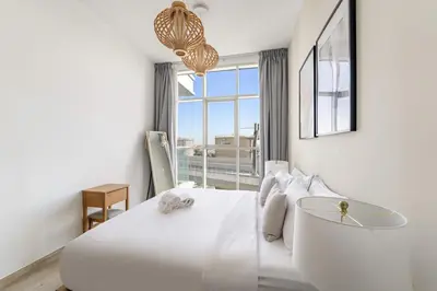 a white bedroom with a large bed and a window at FIRST CLASS 1BR Elegant Marina Hideaway in Dubai