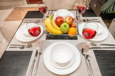 a table with a bowl of fruit and glasses of wine at Charming Old Town Dubai 2BR Retreat with Burj Khalifa Balcony View in Dubai