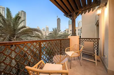 a balcony with chairs and tables and a view of the city at Charming Old Town Dubai 2BR Retreat with Burj Khalifa Balcony View in Dubai