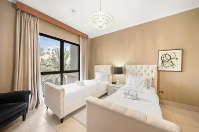 a bedroom with two beds and a couch and a window at Charming Old Town Dubai 2BR Retreat with Burj Khalifa Balcony View in Dubai