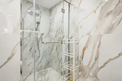 a shower with a ladder in a bathroom with marble walls at Premium 1BR with Iconic Skyline Views with Balcony & Pool in Dubai