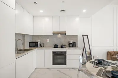 a kitchen with white cabinets and a table at Premium 1BR with Iconic Skyline Views with Balcony & Pool in Dubai