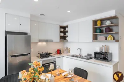 a kitchen with white cabinets and a wooden table at Vogue Downtown Views II with Direct Access to Dubai Mall Via a Climate Controlled Bridge, Two Bedroom Apartment with Balcony and Burj Khalifa View in Dubai