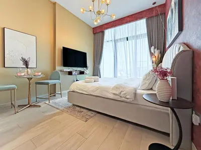 a bedroom with a large bed with a window and a table at Prime Studio Apt at Azizi Riviera 45, Meydan in Dubai