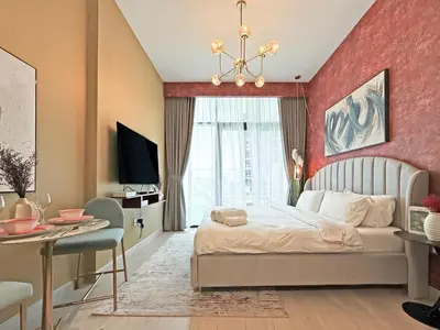 a bedroom with a large bed and a desk and a chair at Prime Studio Apt at Azizi Riviera 45, Meydan in Dubai