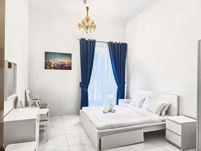 a white room with a bed and a blue curtain at MK Residence JVC in Dubai