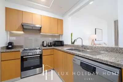 a kitchen with wooden cabinets and a stove top oven at LUX The Executive Burj Khalifa View Suite 2 in Dubai