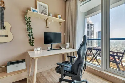 a desk with a computer and a chair in a room with a window at GuestReady - Modern urban retreat in JLT in Dubai
