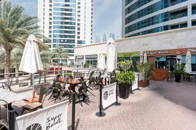 a row of tables and umbrellas on a sidewalk at GuestReady - Modern urban retreat in JLT in Dubai