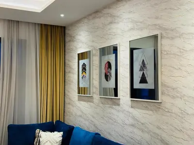a room with four pictures on a wall with a blue couch at Peaceful 2 Bed Oasis Suite in JVC in Dubai