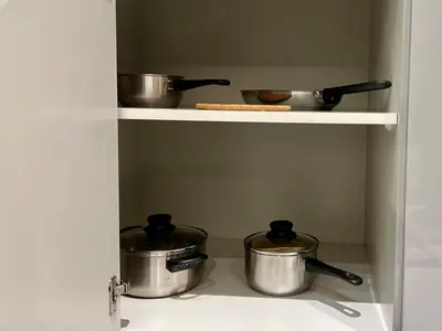 three pots and pans on a shelf in a kitchen at Peaceful 2 Bed Oasis Suite in JVC in Dubai