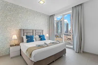 a bedroom with a large bed and a large window at Serene 2-bedroom Escape with Sea Steps Away in JBR in Dubai