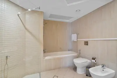 a bathroom with a tub and a toilet and a sink at Serene 2-bedroom Escape with Sea Steps Away in JBR in Dubai