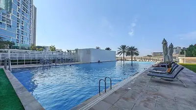 a large swimming pool with chairs and umbrellas at Serene 2-bedroom Escape with Sea Steps Away in JBR in Dubai
