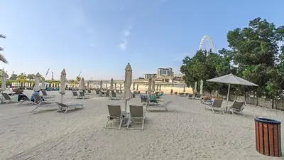 a group of chairs and umbrellas on a beach at Serene 2-bedroom Escape with Sea Steps Away in JBR in Dubai