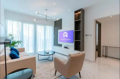 a living room with a tv and a couch and a table at AWS Holiday Homes - Style in Downtown in Dubai