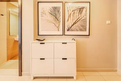 a white dresser in a bathroom with two pictures on the wall at Elegant 1 Bedroom in Botanica Tower Marina in Dubai