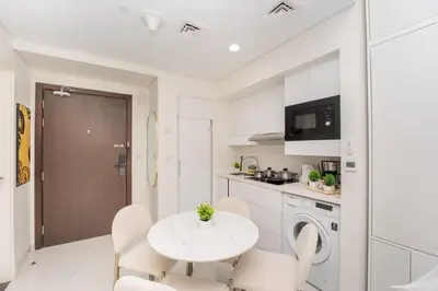 a white kitchen with a white table and chairs at Designer 1BR I Golf View I Comfortably Sleeps 4 in Dubai