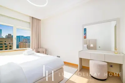 a bedroom with a white bed and a large mirror at LUX The Palm Island Shoreline Suite in Dubai