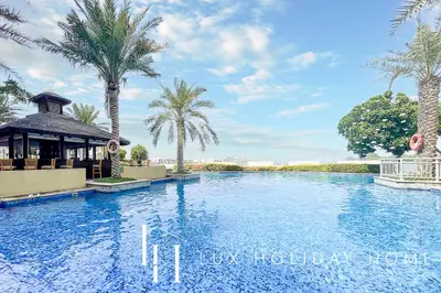 a swimming pool with palm trees and a gazebo at LUX The Palm Island Shoreline Suite in Dubai